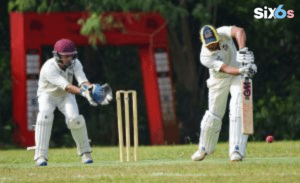 batsman holding a bat and another person stand behind the wickets in world cup ground